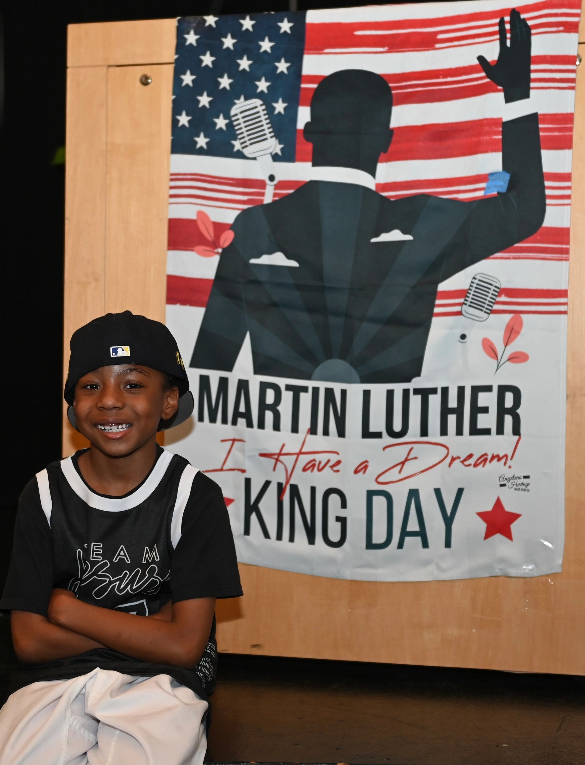 Young boy smiling in front of Martin Luther King Jr. Day poster.