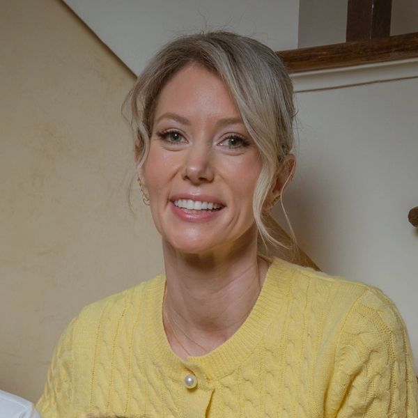 Smiling woman in a yellow sweater with light hair pulled back.