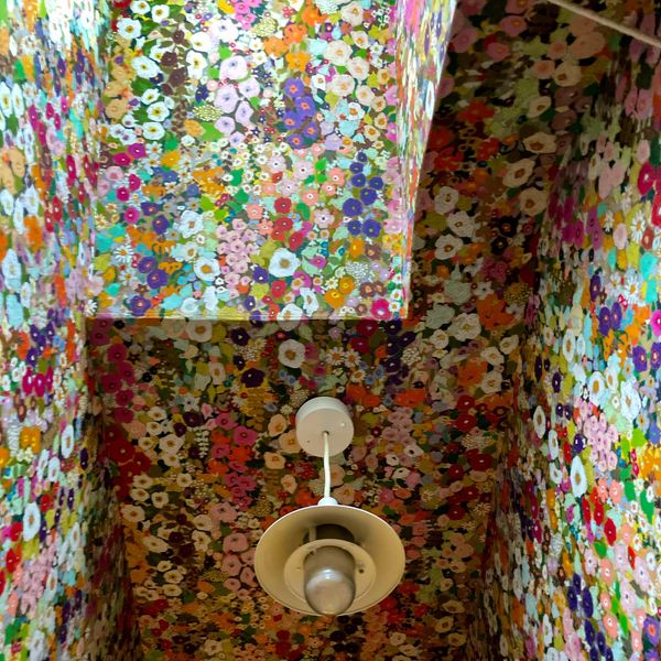 Ceiling covered in vibrant, multicolored floral wallpaper with a central hanging light fixture.