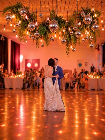 Couple sharing a dance under festive lights and decorations.
