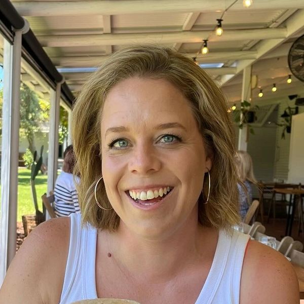 Smiling woman holding a coffee cocktail in an outdoor café.