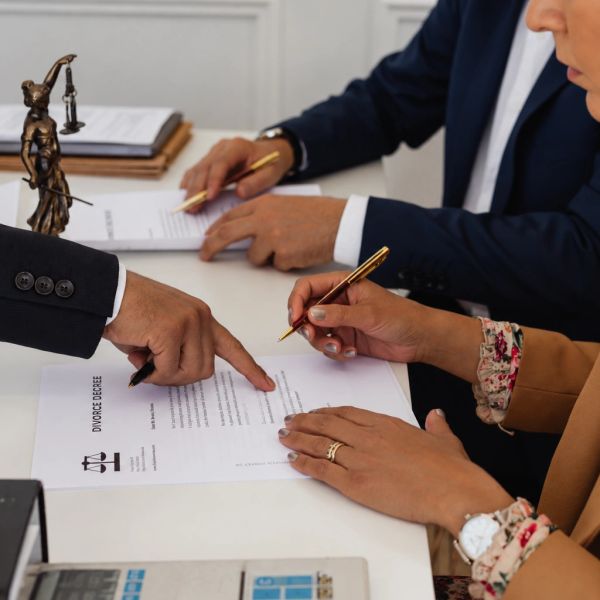 People signing a divorce decree paper at a desk.