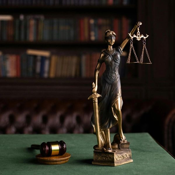Statue of Lady Justice with gavel in a library setting.