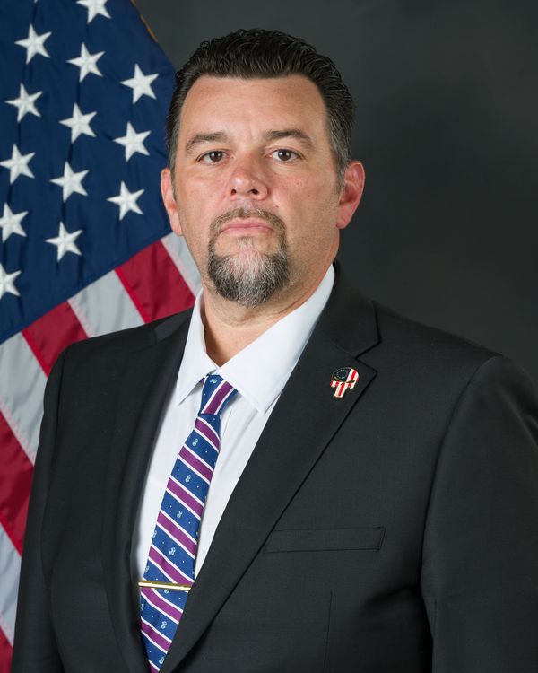 Man in suit with American flag background.