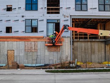 Construction workers use a lift to work on a building's exterior.
