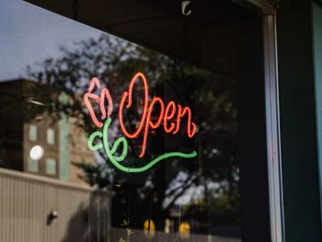Neon "Open" sign with a flower design in a shop window.