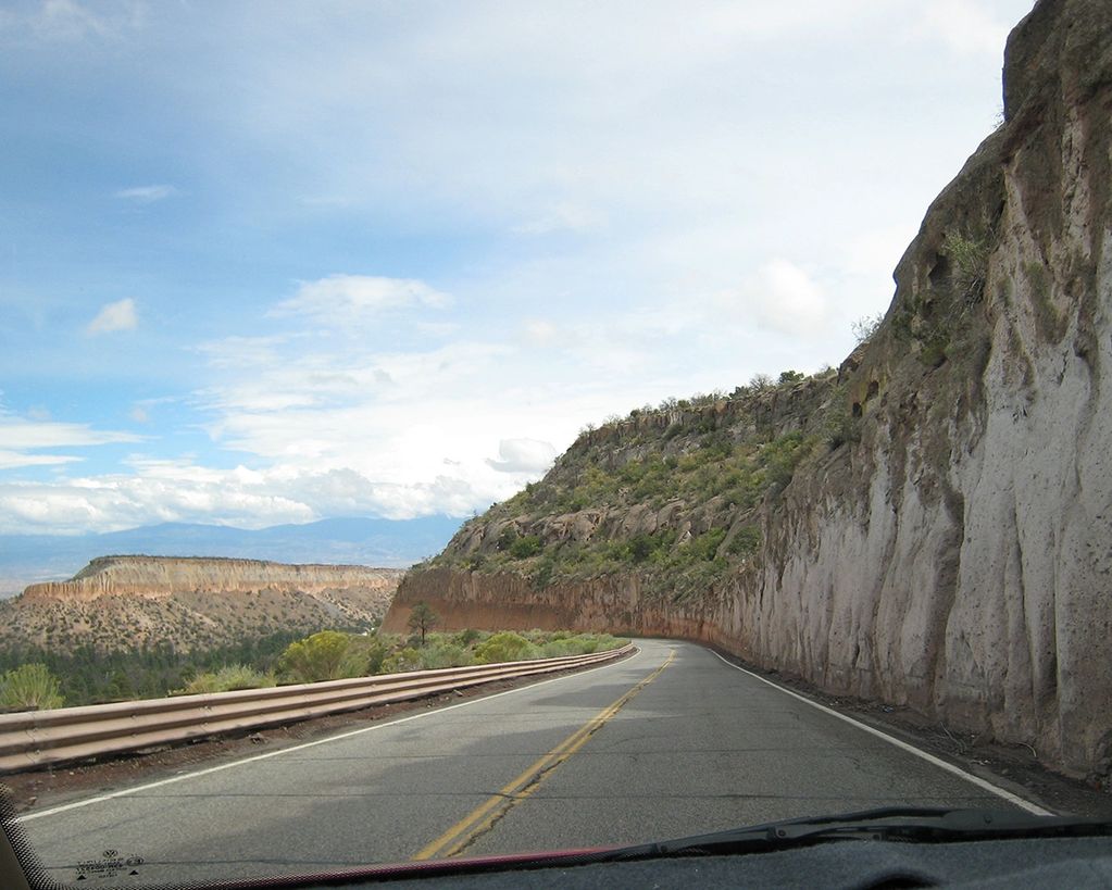 Scenic desert road winding through rocky cliffs under a blue sky.