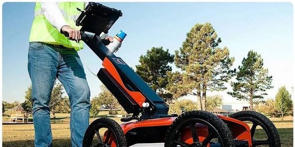 Person using a ground-penetrating radar device outdoors.
