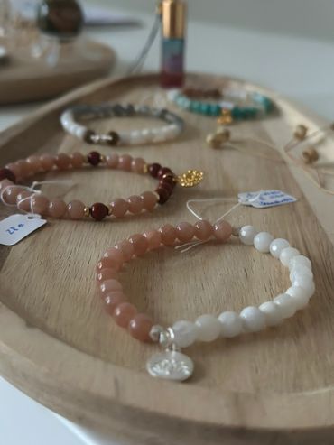 Beaded bracelets with price tags displayed on a wooden tray.