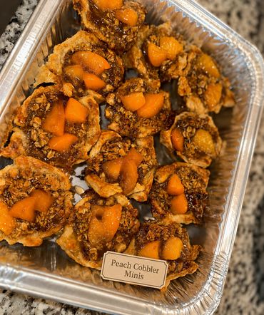 Tray of mini peach cobblers with golden crust and peach chunks.
