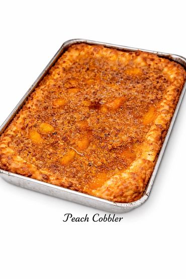 Freshly baked peach cobbler in a metal pan with a crumbly topping.