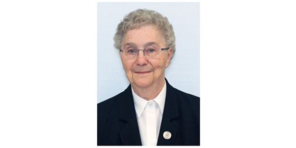 Portrait of an elderly woman in formal attire with glasses.
