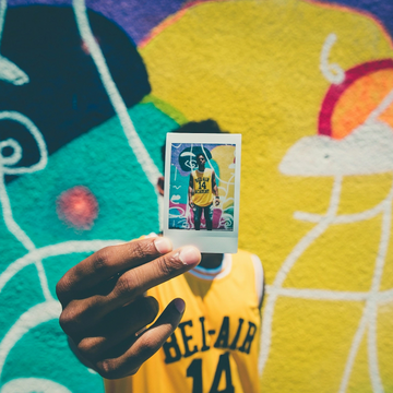 Photo of a man holding a photo of himself in front of a colorful backdrop