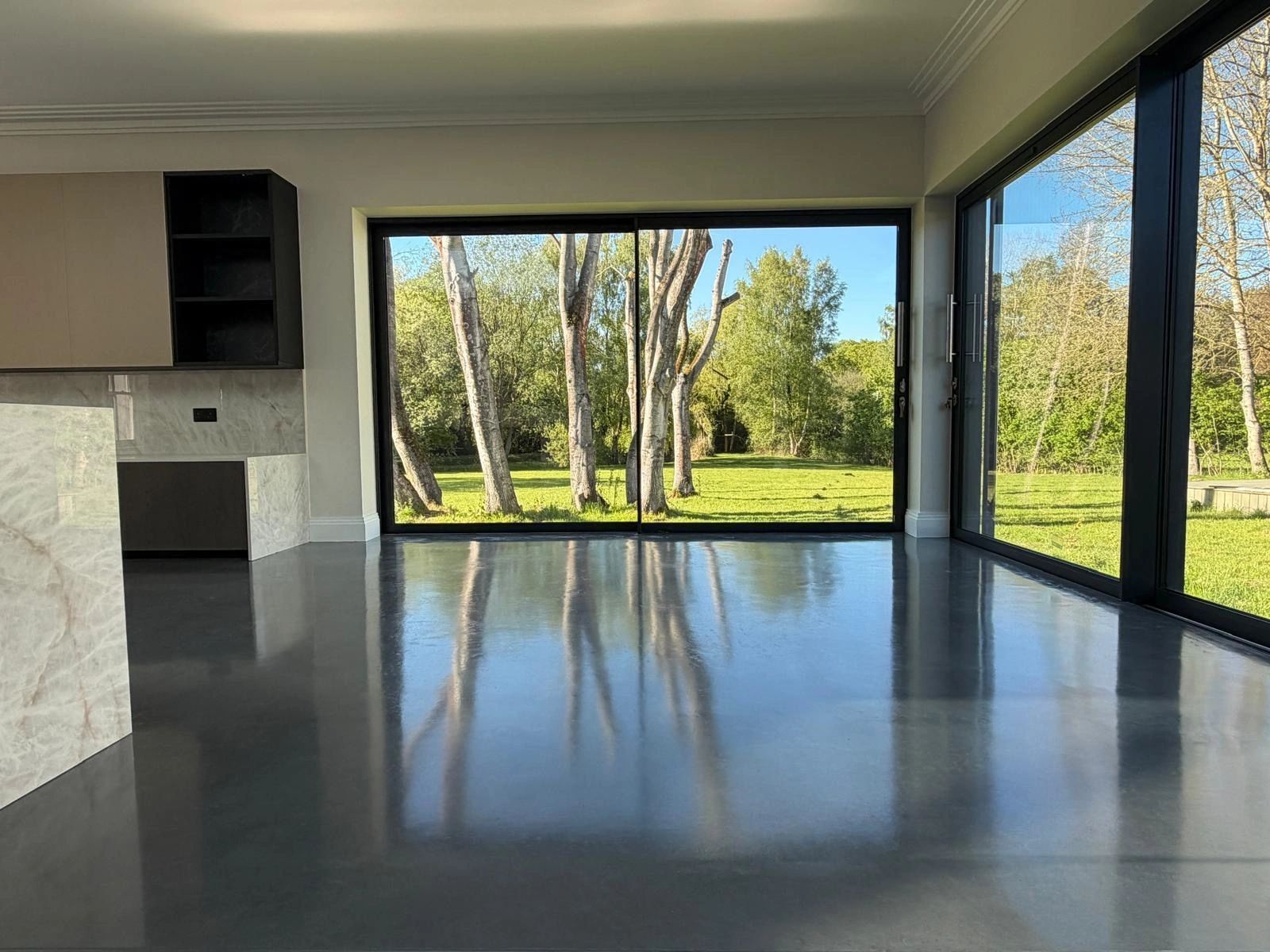 Modern empty room with large glass windows showcasing a green outdoor view.
