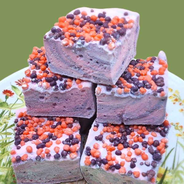 Colorful, sprinkled fudge pieces stacked on a floral plate.