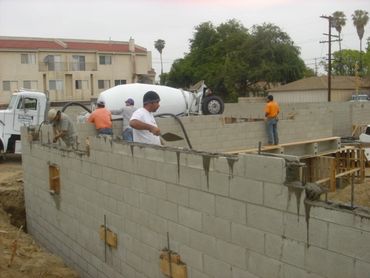 Construction workers building a cinder block wall at a construction site.