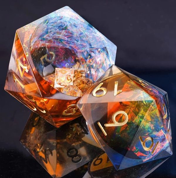 Two colorful, translucent polyhedral dice with gold numbers on a reflective surface.