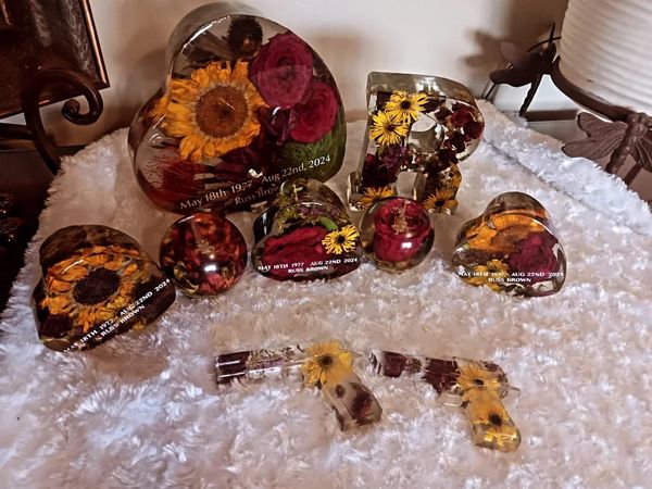 Resin art pieces with flowers and personalized engravings on a plush white surface.