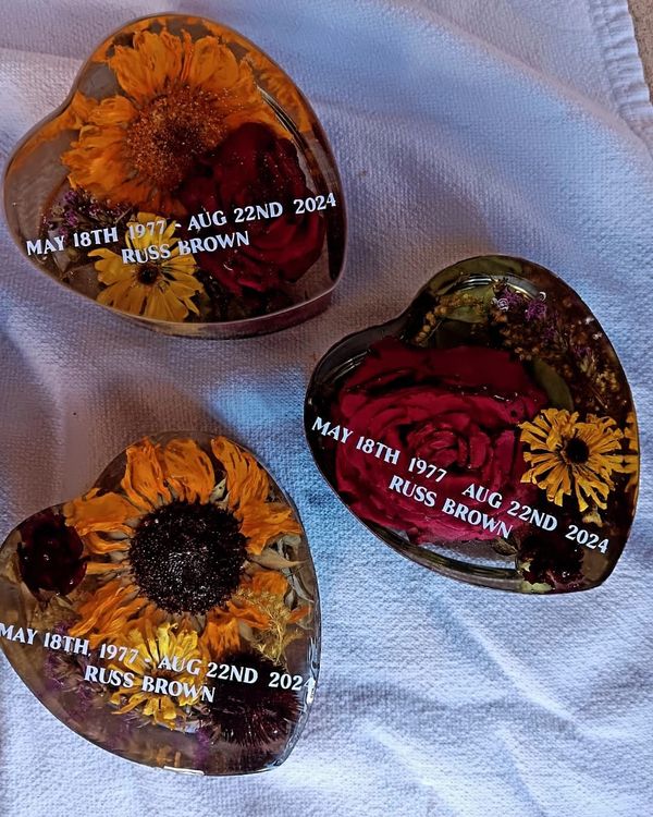 Heart-shaped resin memorials with flowers and dates honoring Russ Brown.