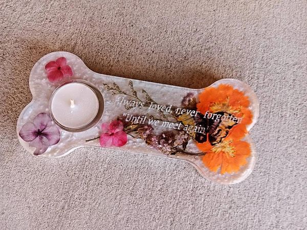 A floral memorial candle holder with the inscription 'Always loved, never forgotten'.