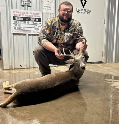 Man posing with a deer he hunted.