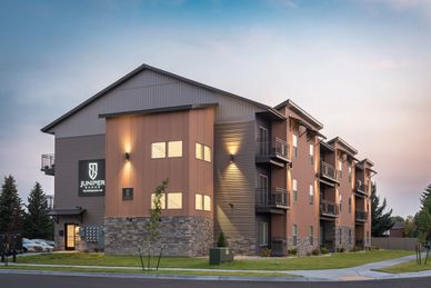 Modern apartment building with warm exterior lighting at dusk.