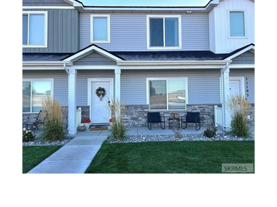 Front view of a modern townhouse with a decorated white door and outdoor seating.