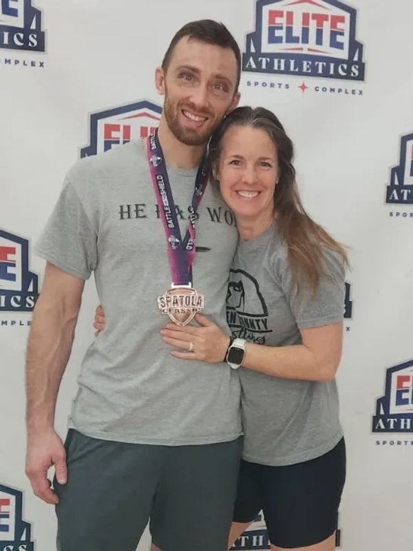 Smiling couple posing with a medal at Elite Athletics event.
