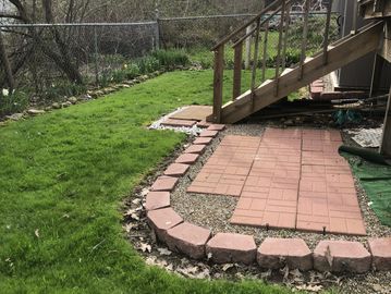 Backyard patio with stone steps and green grass.