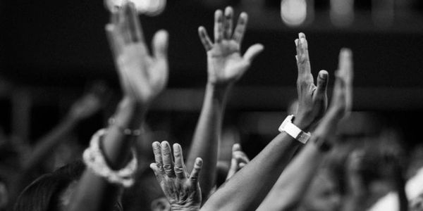 Raised hands in a crowd, black and white photo.