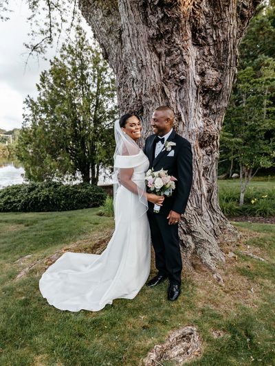 A couple posing by a tree at Rachel's Lakeside wedding venue