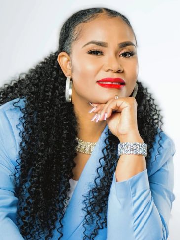 Woman with curly hair and red lipstick, wearing a blue outfit.