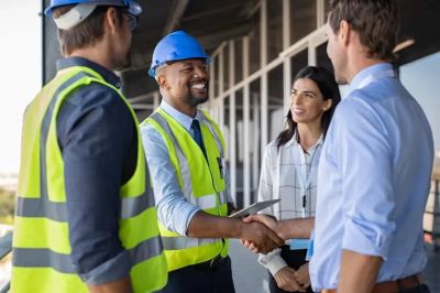 Engineers and business people shaking hands at a construction site.