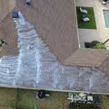 A roof with a large patched area covered in white material.