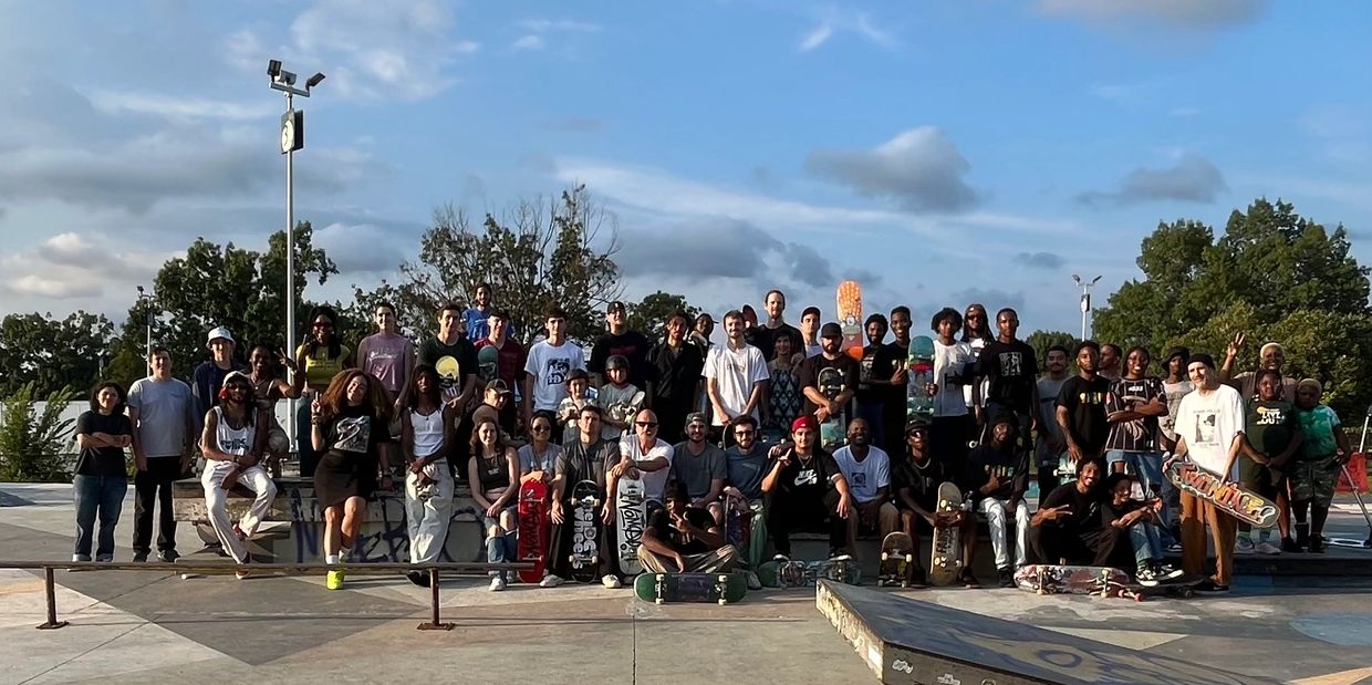 Large group of skateboarders posing with skateboards.
