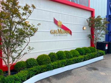 Decorative garden with GH Mumm Champagne sign on wall.