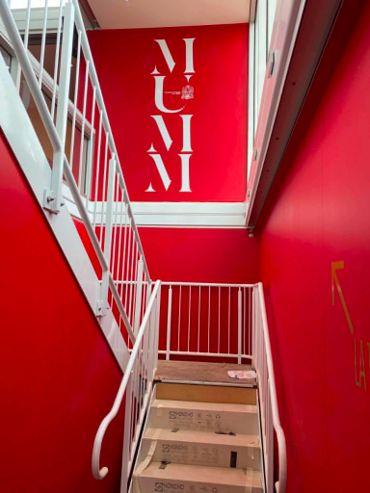 Red stairwell with white railing and inverted text on the wall.