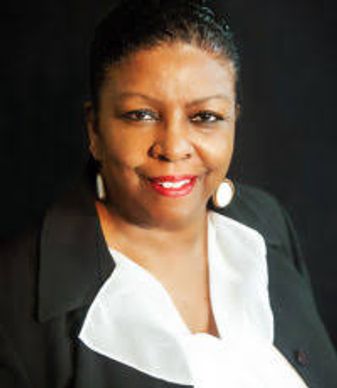 Professional woman in black blazer and white blouse smiling.