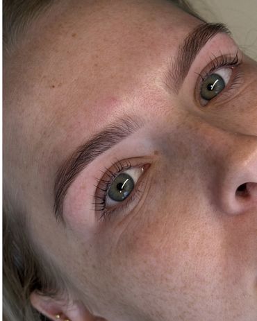Close-up of a person's face highlighting their natural freckles and green eyes.