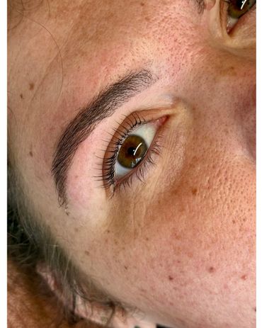 Close-up of a brown eye with detailed skin texture and eyebrow.