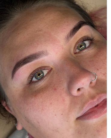 Close-up of a face with freshly groomed eyebrows and a nose ring.