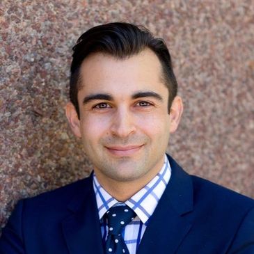 Professional man in a navy suit and polka dot tie smiling.