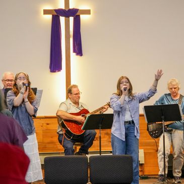A church band performing with a cross in the background.