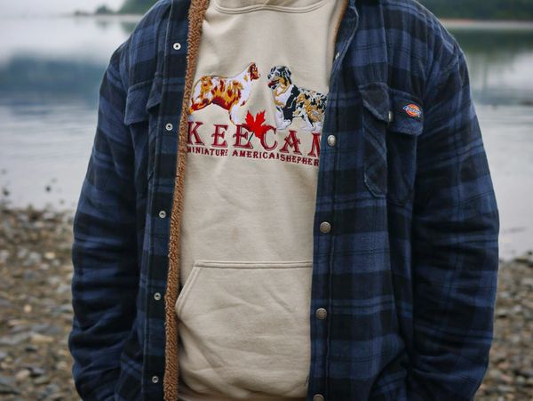Person wearing a beige sweatshirt with dog prints and a blue plaid jacket.