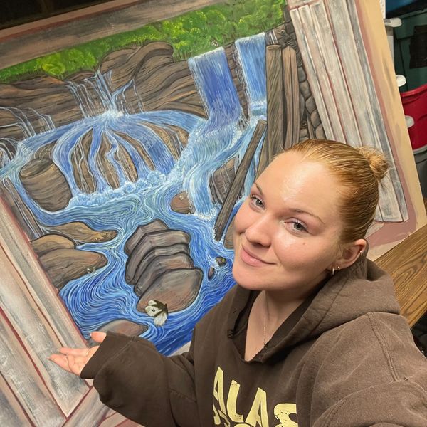 Woman posing with a 3D waterfall painting on the wall.