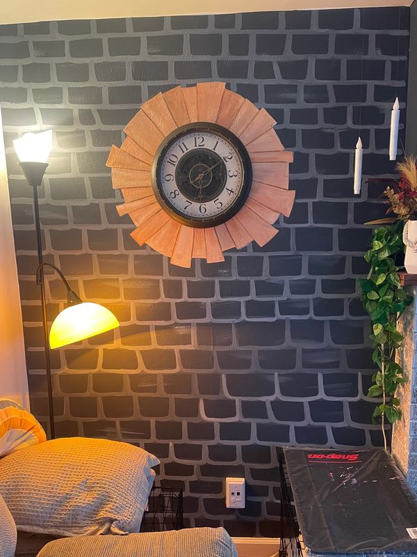 Cozy corner with a wall clock, two lamps, and patterned wall.