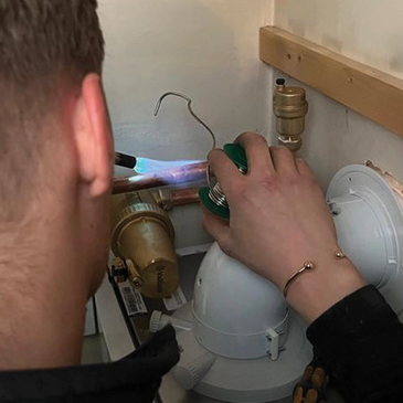 Gas engineer soldering pipework for a replacement heating boiler.  