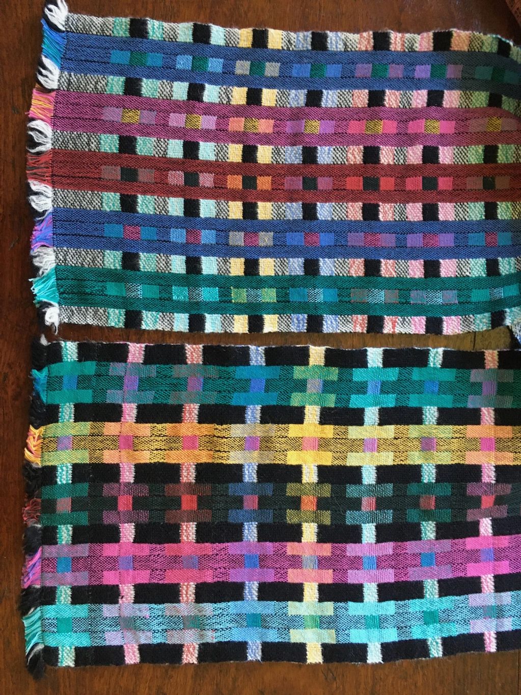 Handwoven scarf in pattern of coloured vertical stripes on a black and white background.