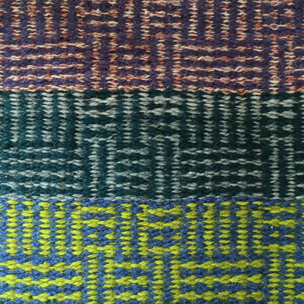 Close up of hand woven wool rug in stripe and check pattern of greys, purple, dark green and lime.
