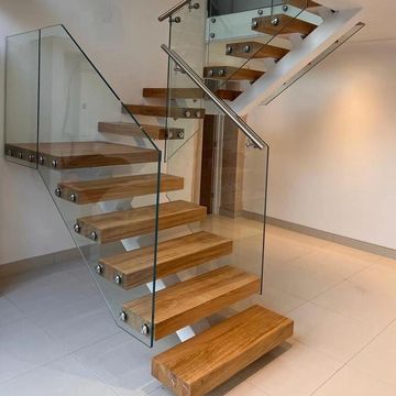 Modern wooden staircase with glass railing.
